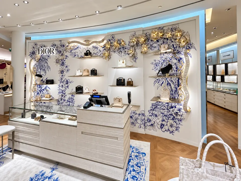 Boutique Dior pour les fêtes : décor d'hiver botanique bleu et blanc rehaussé d'or au-dessus des présentoirs.
