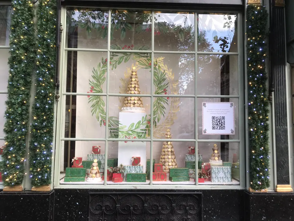 Décoration de vitrine de Noël Ladurée : couronnes et frise de feuillage en vitrophanie sur une vitrine à petits bois