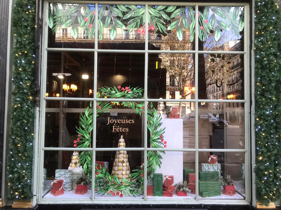 Vitrophanie de Noël Ladurée : couronne de feuillage et baies rouges imprimée sur la vitrine, message « Joyeuses Fêtes »