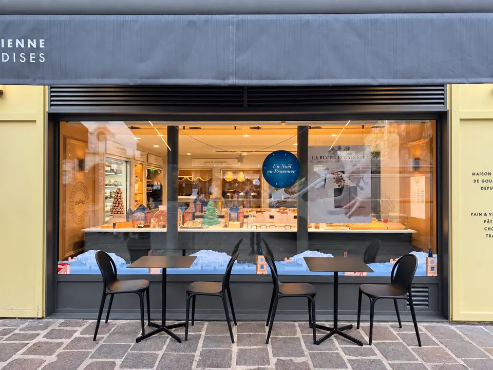 Boutique Lenôtre avec terrasse : vitrine de Noël « Un Noël en Provence », village et montagnes enneigées en vitrophanie en partie basse.