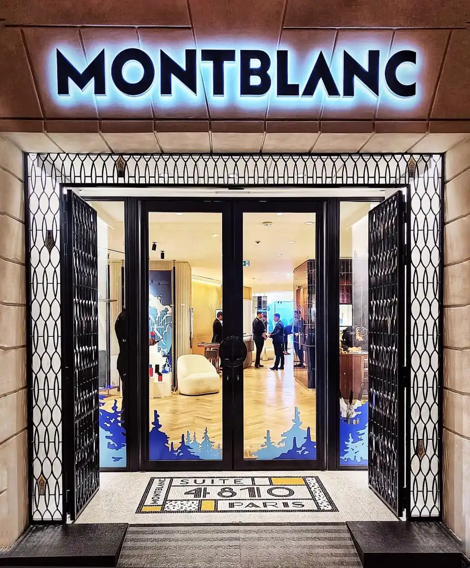 Entrée de la boutique Montblanc en décembre : forêt de sapins bleus enneigés en vitrophanie au bas des portes vitrées.